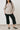 Woman wearing a beige shirt and black pants against a white background