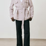 Person wearing a light pink blazer and black pants against a white background