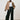 model wearing a camel jacket, white shirt, and black pants on a plain background