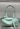 Mint green handbag with a strap on a gray background