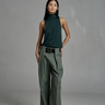 Person wearing a green sleeveless top and wide-leg pants against a gray background